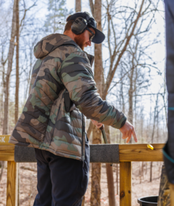 Man in a camo jacket tossing used shells in trash on the Blue Course at EVSC.
